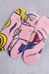 Skateboard Art print from Roy Lichstentein famous Kiss V painting laying on a concrete floor