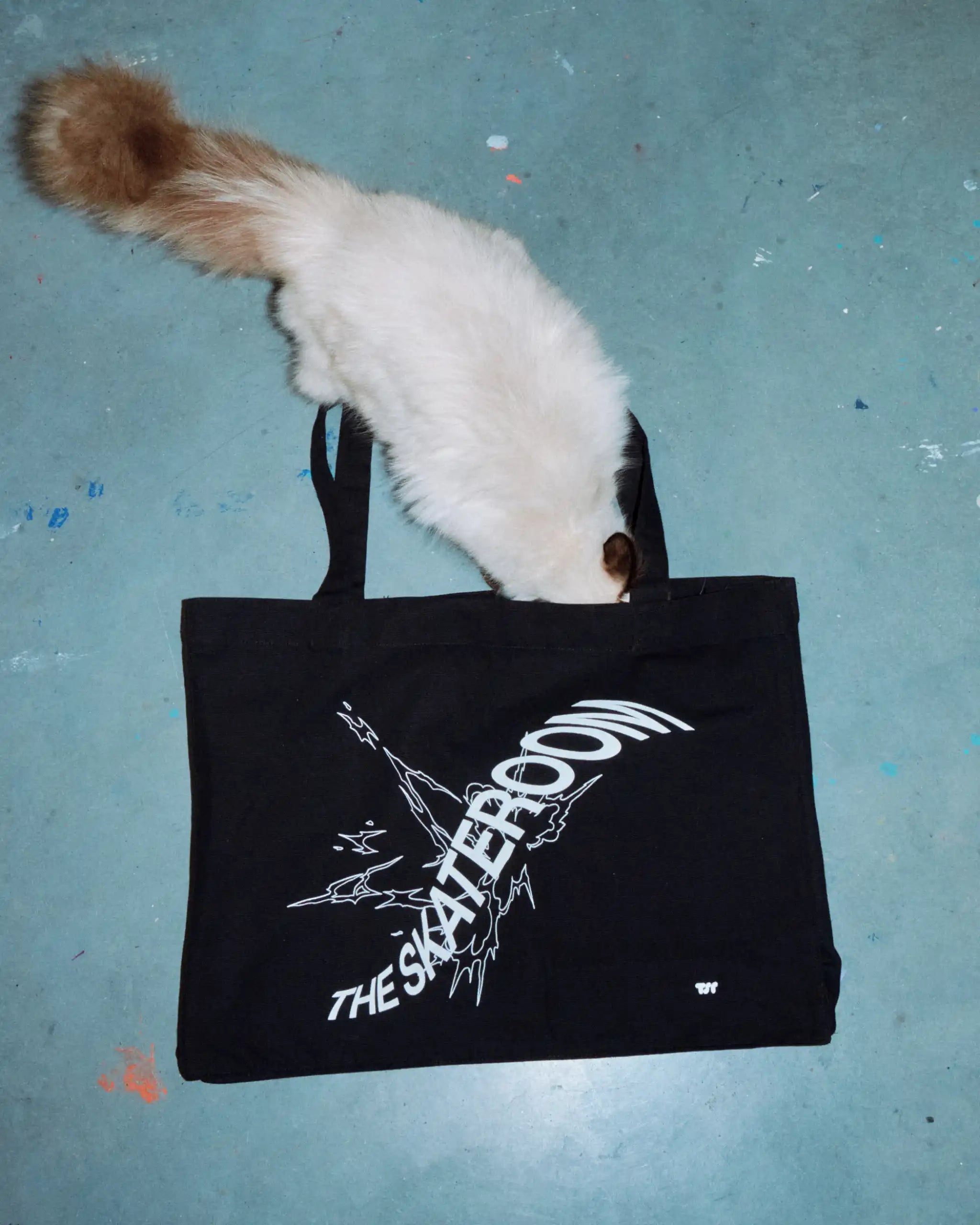 Minimalist black canvas tote bag with white print, styled against a concrete backdrop — sustainable design meets utilitarian streetwear.