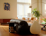 Modern living room with a brown leather sofa, wooden coffee table, and decorative items, including Blue Nude II skate triptych by Henri Matisse.