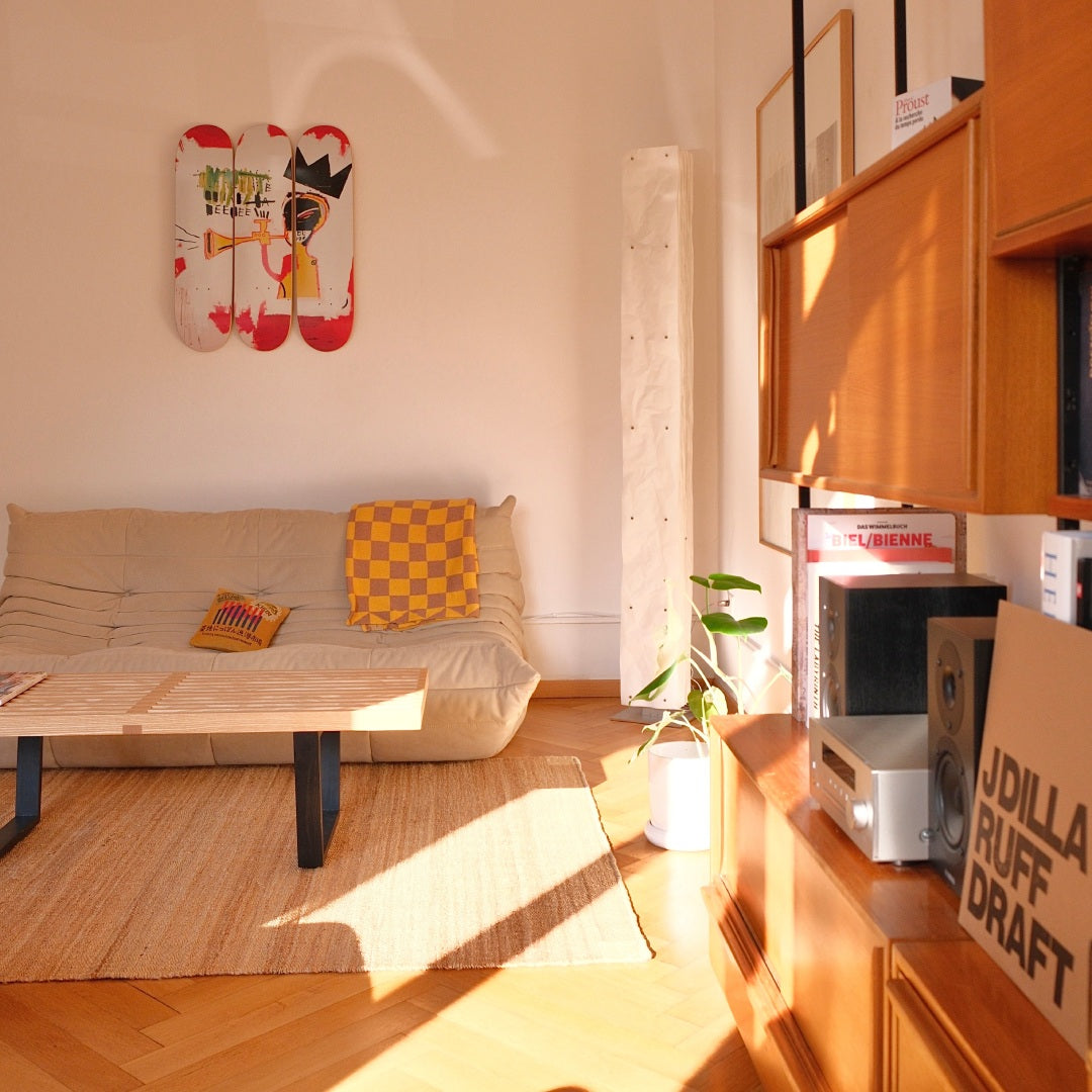 Jean-Michel Basquiat "Trumpet" skateboard wall art by THE SKATEROOM in a japandi interior apartment, above a Ligne-Roset Togo sofa