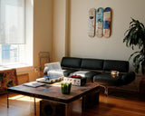 Living room with a black sofa, coffee table, and decorative items including Charles The First skate triptych by Jean-Michel Basquiat.