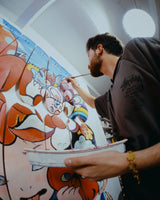 Close-up of artist VEXX painting fine details onto his ‘The Life of the Party’ mural across mounted skate decks in his studio.