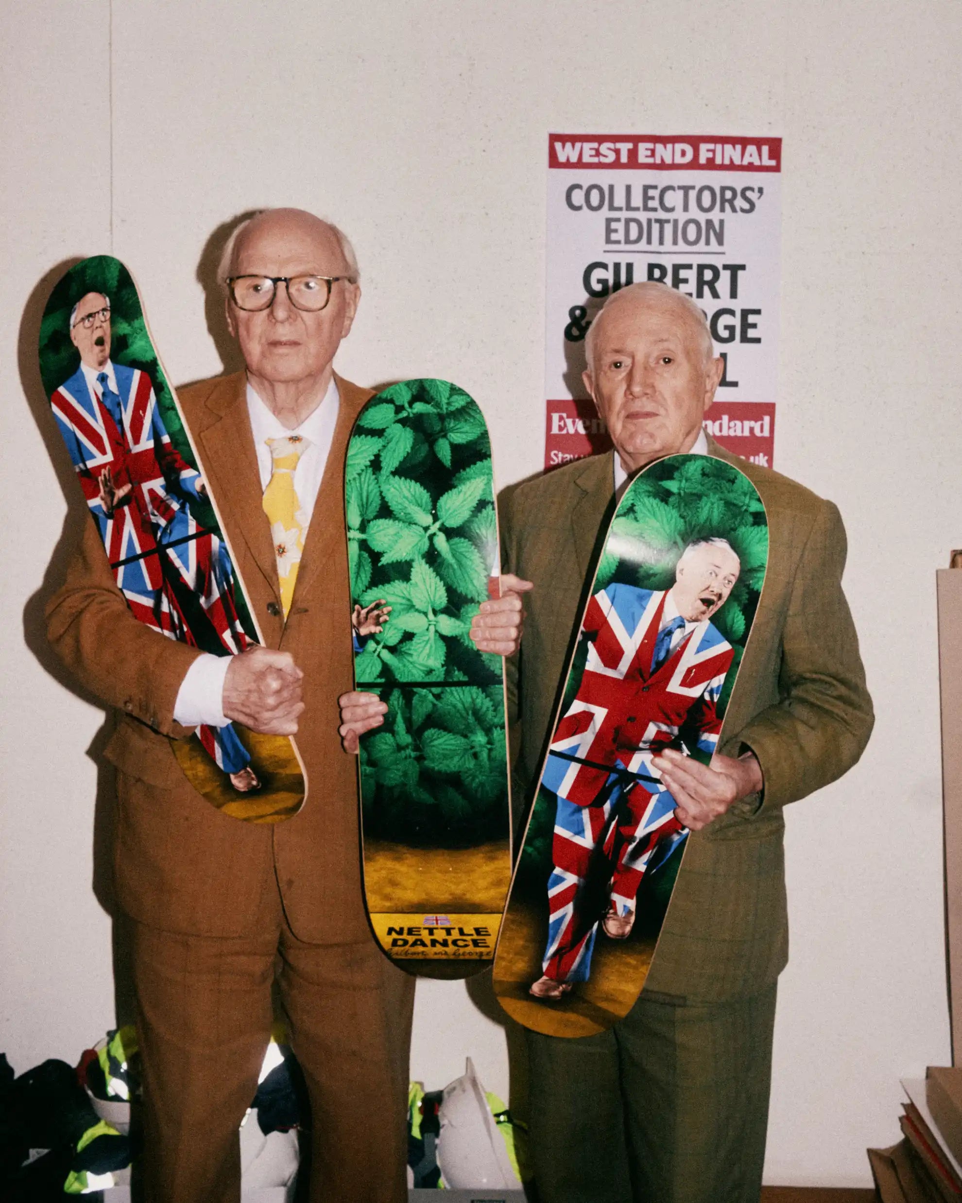 Gilbert & George holding their "The Nettle Dance" skateboard triptych by THE SKATEROOM in their London Studio.