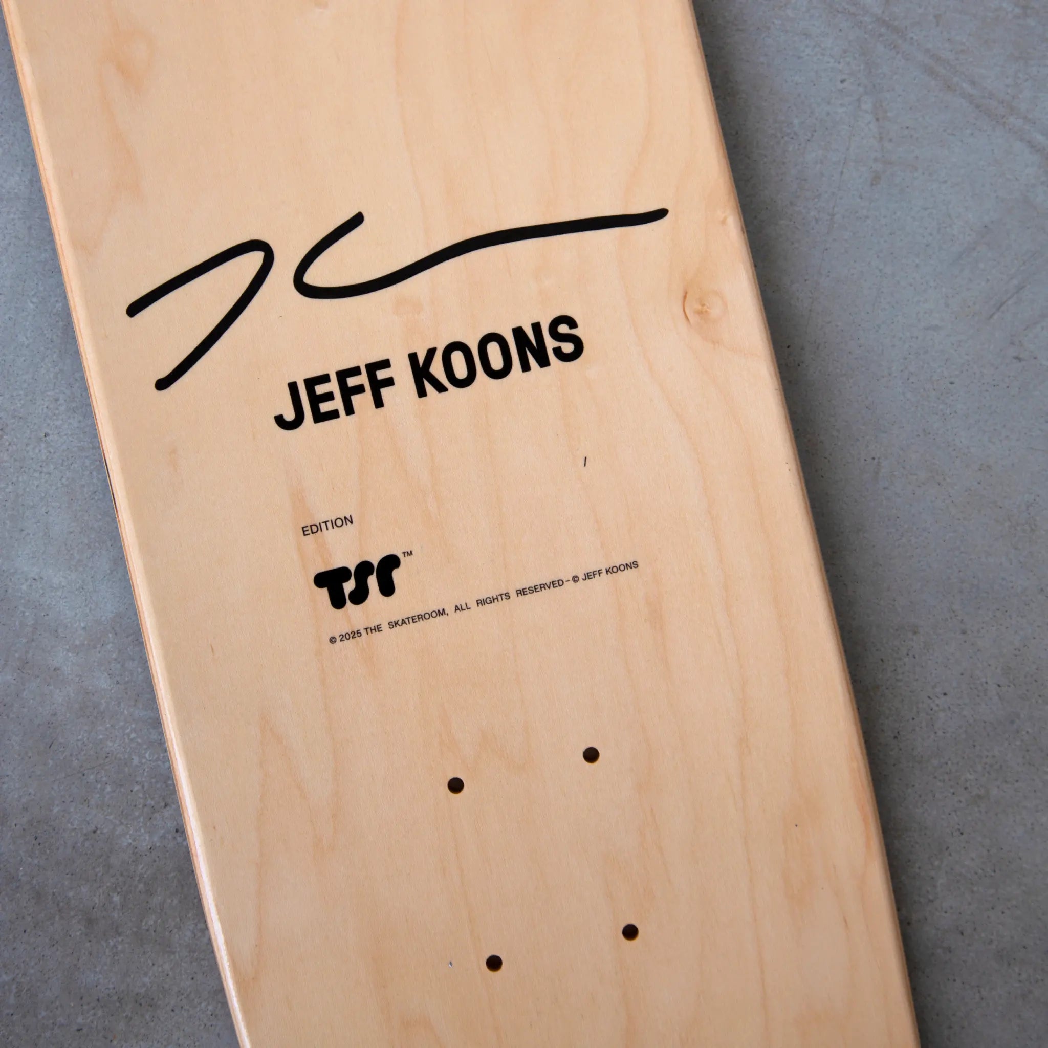 Close-up of Jeff Koons signature and edition details on the natural wood skateboard deck by THE SKATEROOM, 2025.