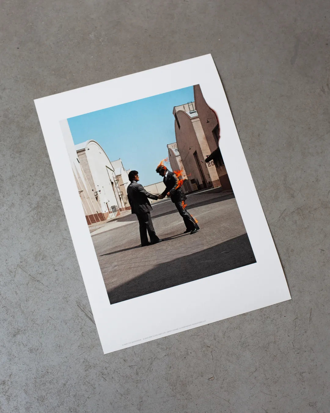 The Wish You Were Here (Burning Man) giclée print by THE SKATEROOM and Pink Floyd on a concrete floor.