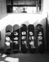 Jim Jarmusch’s ‘TV Photos’ skate deck collection displayed in a striking black-and-white composition. The legendary filmmaker is reflected in the mirror above, adding a cinematic touch to the scene.