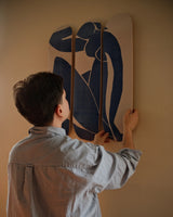 A person carefully hanging the Henri Matisse 'Blue Nude' triptych skate deck on a wall, showcasing its elegant artistry and versatility as a decorative piece.