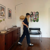 A person walks past the 'In Italian' Basquiat triptych skateboard art displayed on a wall, featured as part of a stylish, minimalist room's decor.