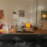 Modern living room featuring a Jean-Michel Basquiat skateboard triptych by THE SKATEROOM on the wall, complemented by mid-century furniture, a cozy paper lantern, and a coffee table adorned with art books, creating a sophisticated and artistic ambiance.