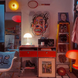 Interior design showcasing a vibrant art display featuring three skate decks with Jean-Michel Basquiat’s Face artwork mounted on the wall. The space is accented with modern furnishings, a vintage tennis racket, books, and a basketball, creating a stylish, eclectic aesthetic.