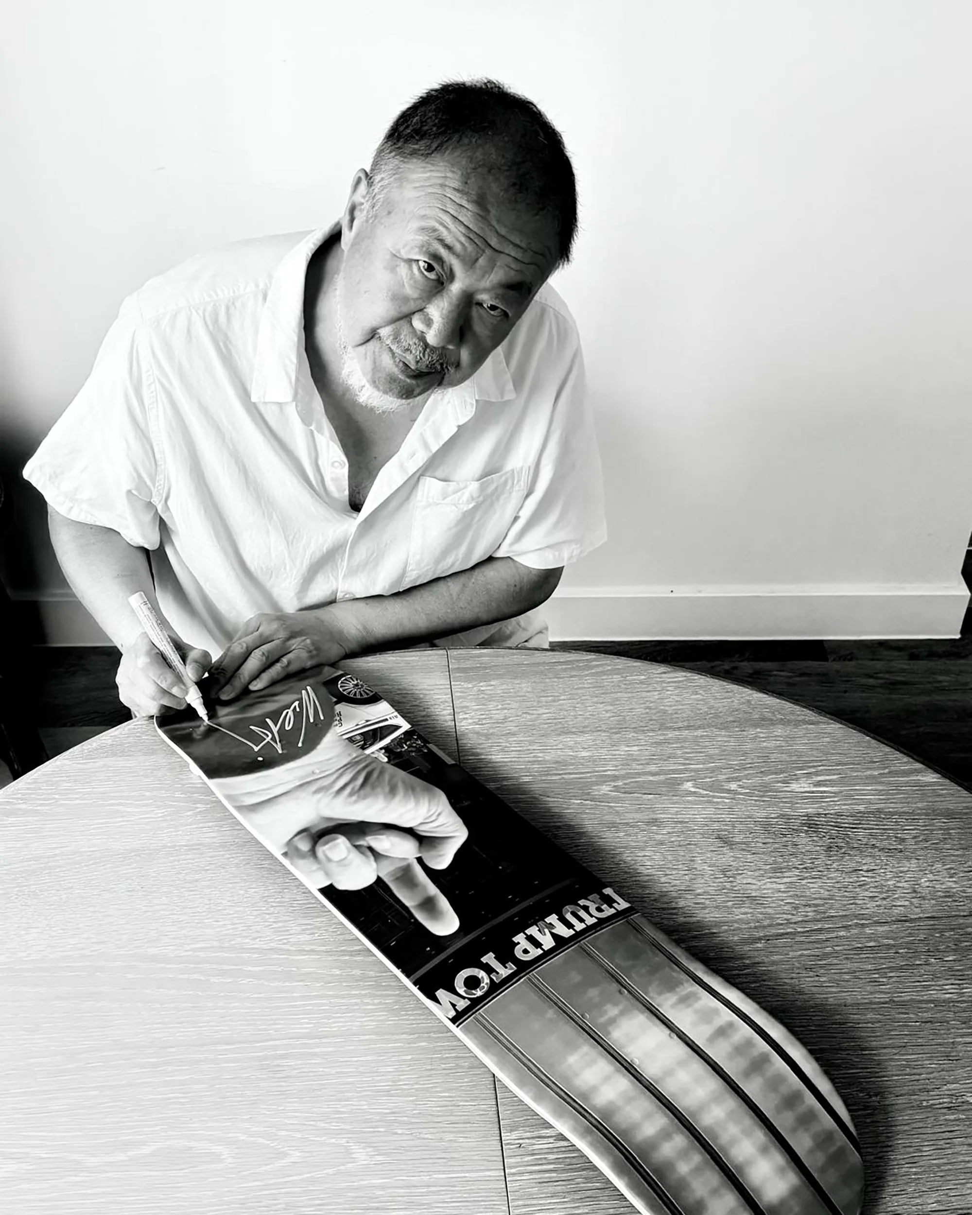 Ai weiwei signing a skate deck by the skateroom