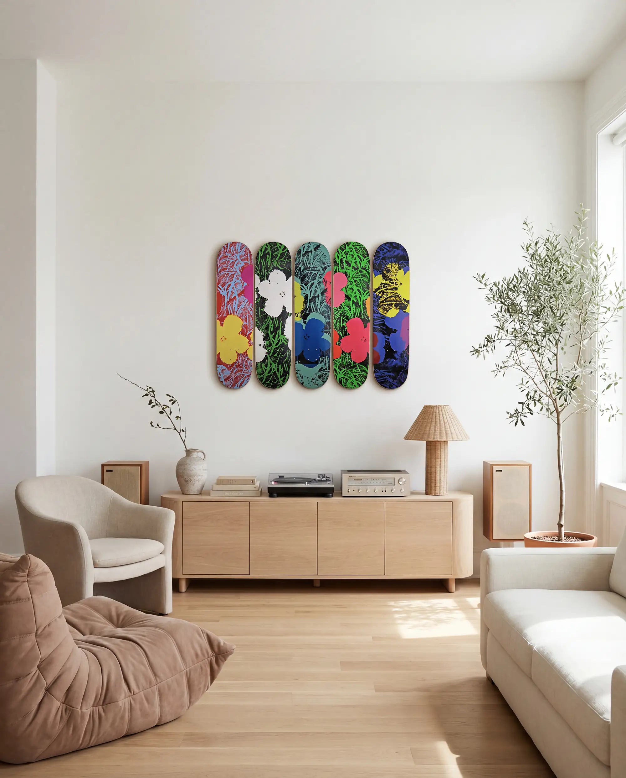 Colorful skateboard decks by Andy Warhol and THE SKATEROOM on a wall in a modern living room, next to a Togo sofa by Ligne Roset and modern japandi credenza.