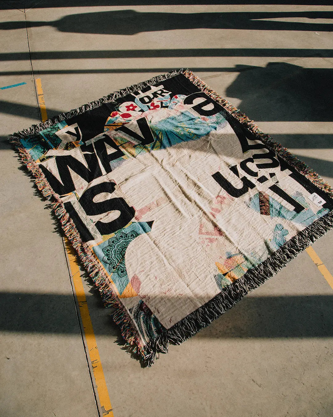 Woven blanket by artist David Carson on a concrete floor, perfect gift for art and design lovers, made by THE SKATEROOM.