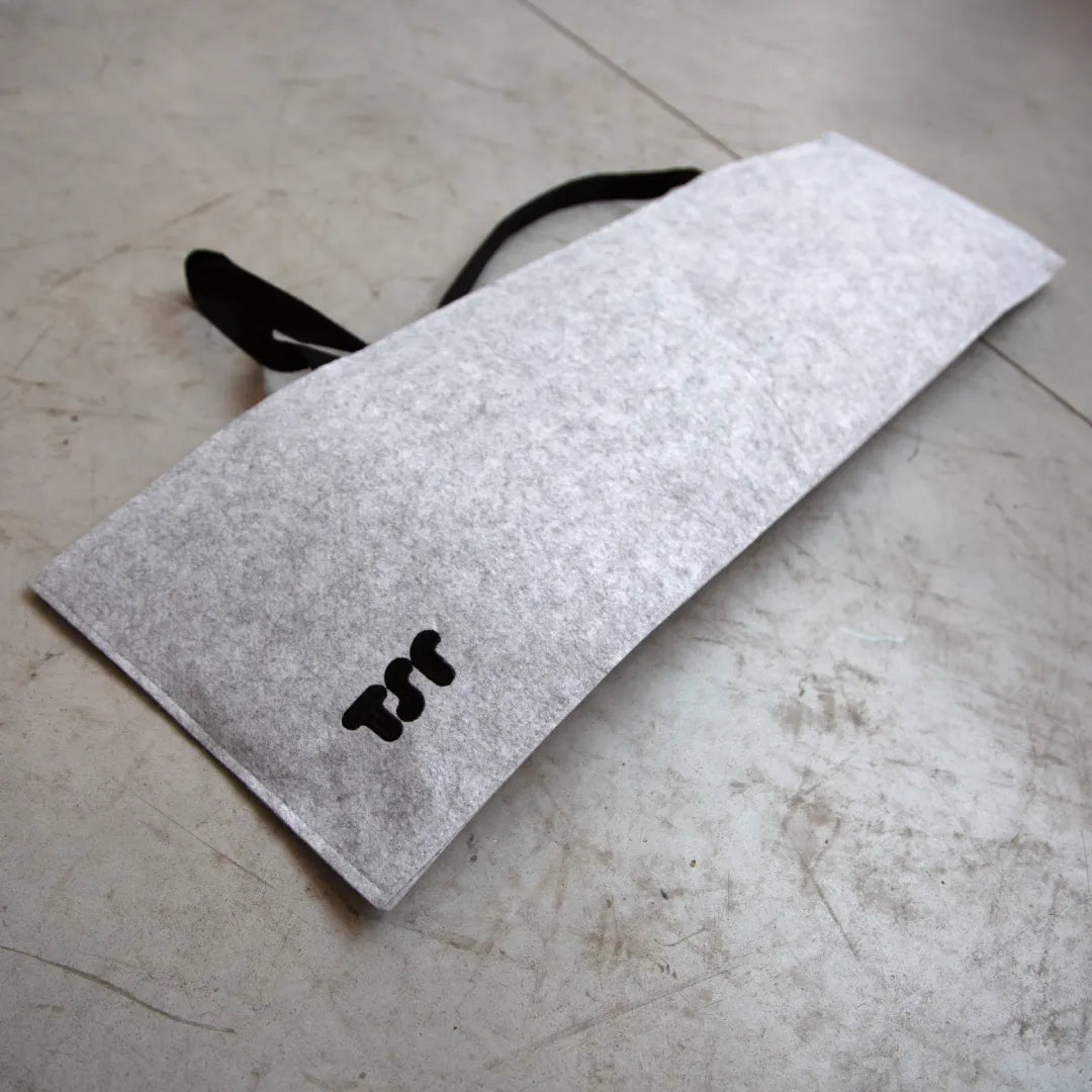 THE SKATEROOM medium felt bag displayed on a concrete surface, showing minimalist design with black TSR logo.