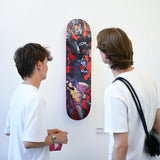 Two visitors admire an expressive skateboard artwork by Korakrit Arunanondchai