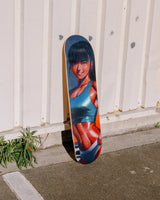 Burning Like a Star art skateboard by Little Thunder leaning against a white corrugated wall outdoors