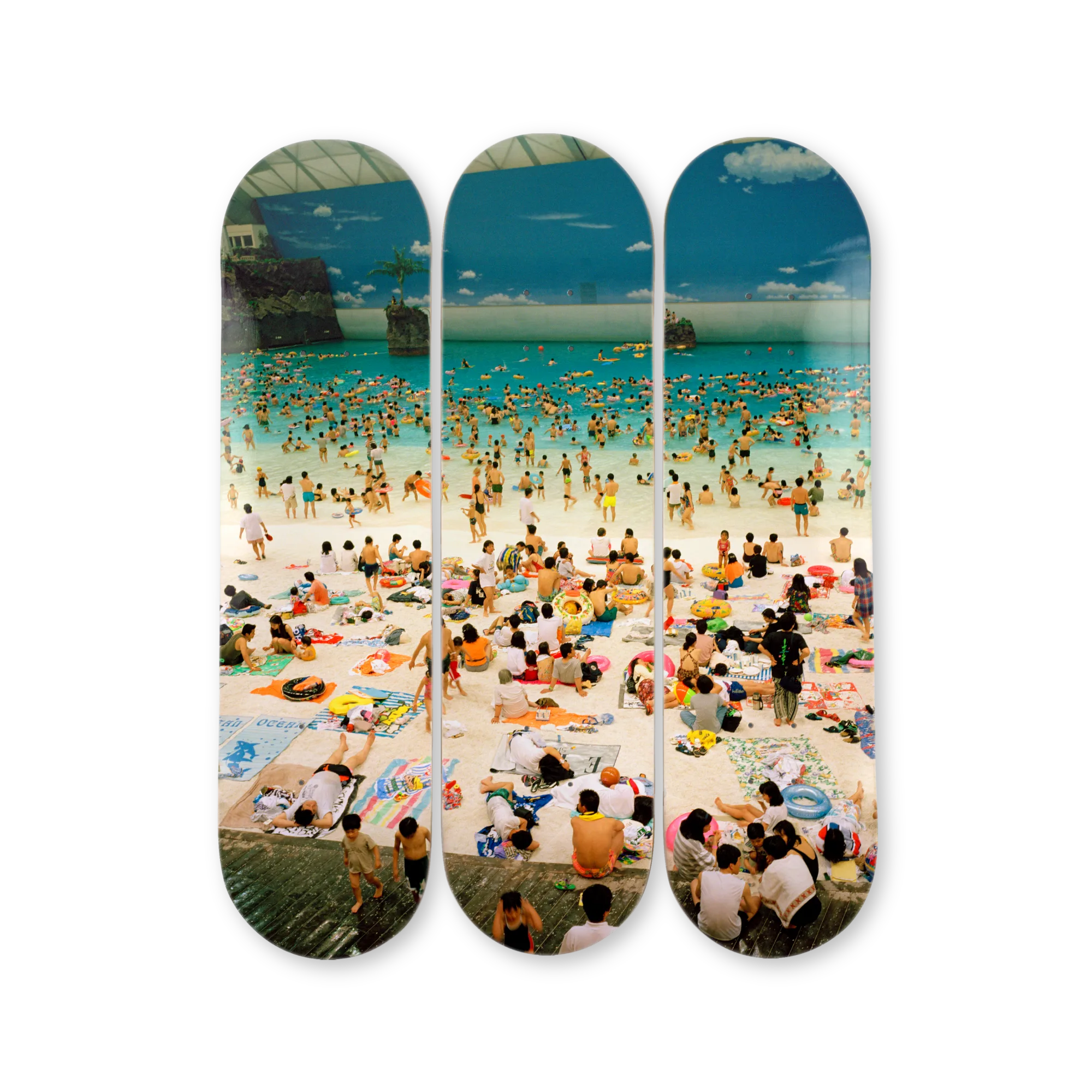 Three skateboard decks with a crowded beach scene photography by Martin Parr printed on them.