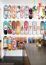 THE SKATEROOM and Supreme art skateboards displayed on a wall in a modern interior.