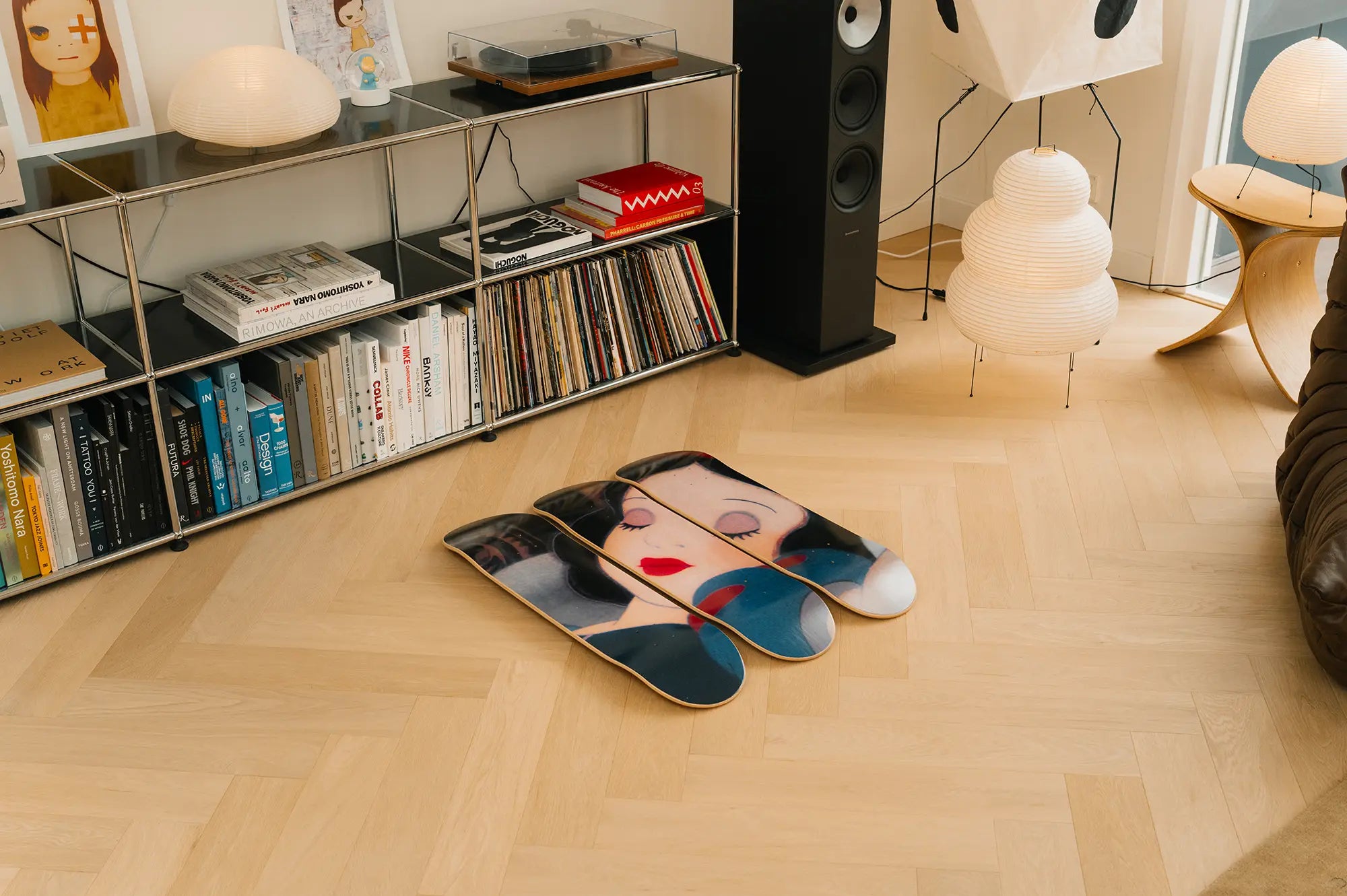 Set of three decorative wall art skate decks with an iconic scene from Disney's Snow White, laying on the floor next to a USM Haller credenza and Yoshitomo Nara art books.